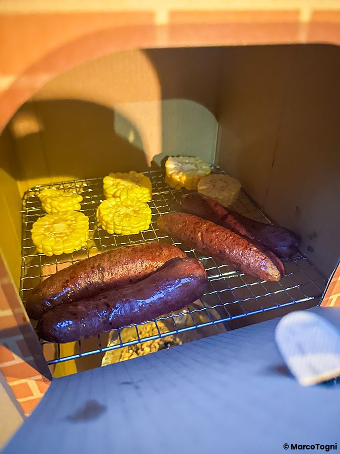 Cibo affumicato in preparazione su griglia con salsicce e pannocchie a Inadani Campers Village.