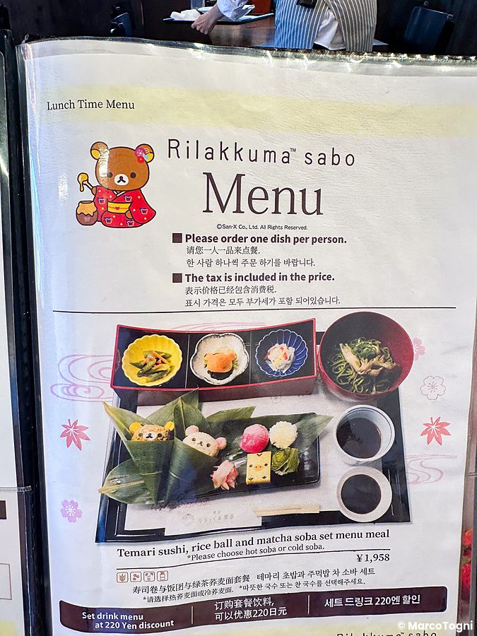 Menu plastificato del ristorante Rillakuma Tea house che illustra un set di sushi e soba ad Arashiyama.