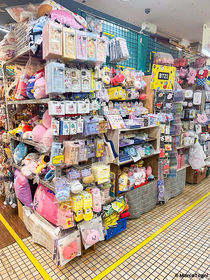 Scaffali pieni di gadget e peluche della linea BT21 esposti all'interno del negozio Village Vanguard.