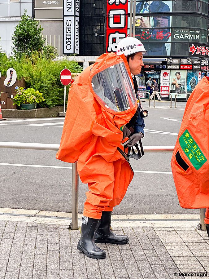 Pompiere a Shinjuku, Giappone, con tuta protettiva arancione in strada.