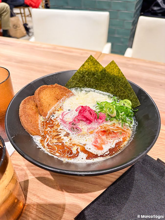 Piatto di ramen vegano con alghe nori e tofu croccante in un ristorante.