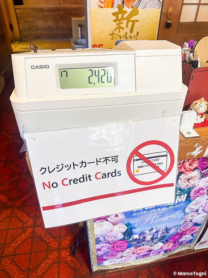 Una cassa registratrice marca Casio su un bancone con un cartello che indica il divieto di pagamento con carta di credito.
