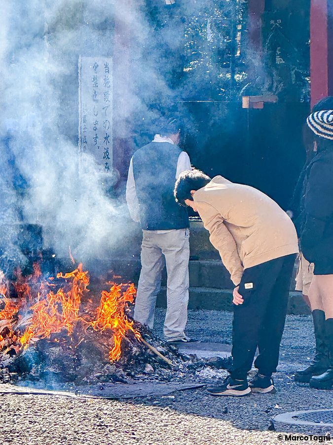 Persone attorno a un fuoco in un santuario giapponese a Capodanno.