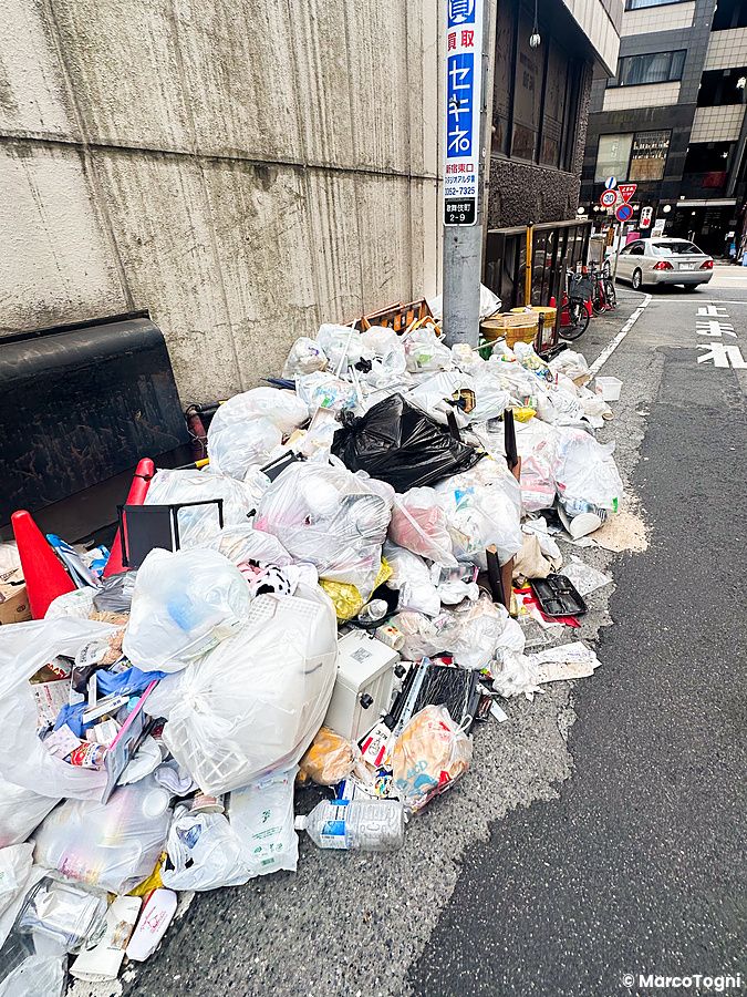 spazzatura ammassata su un marciapiede in una strada urbana in giappone.