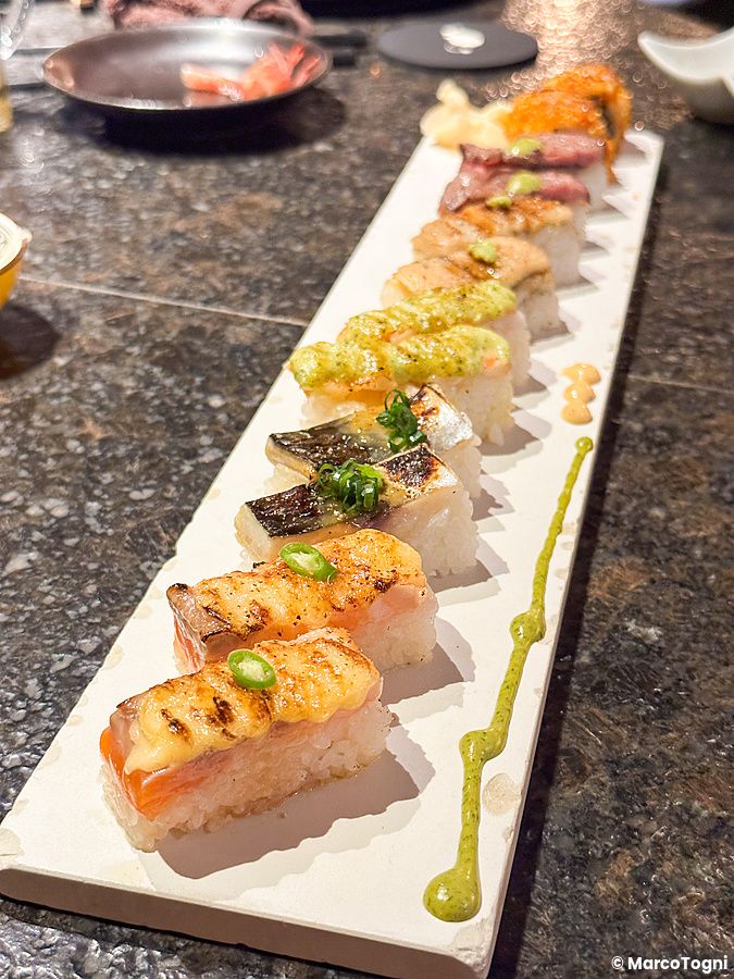 Una fila di sushi aburicious, leggermente scottato, servito su un piatto rettangolare al Kinka Sushi Bar Izakaya a Shibuya.