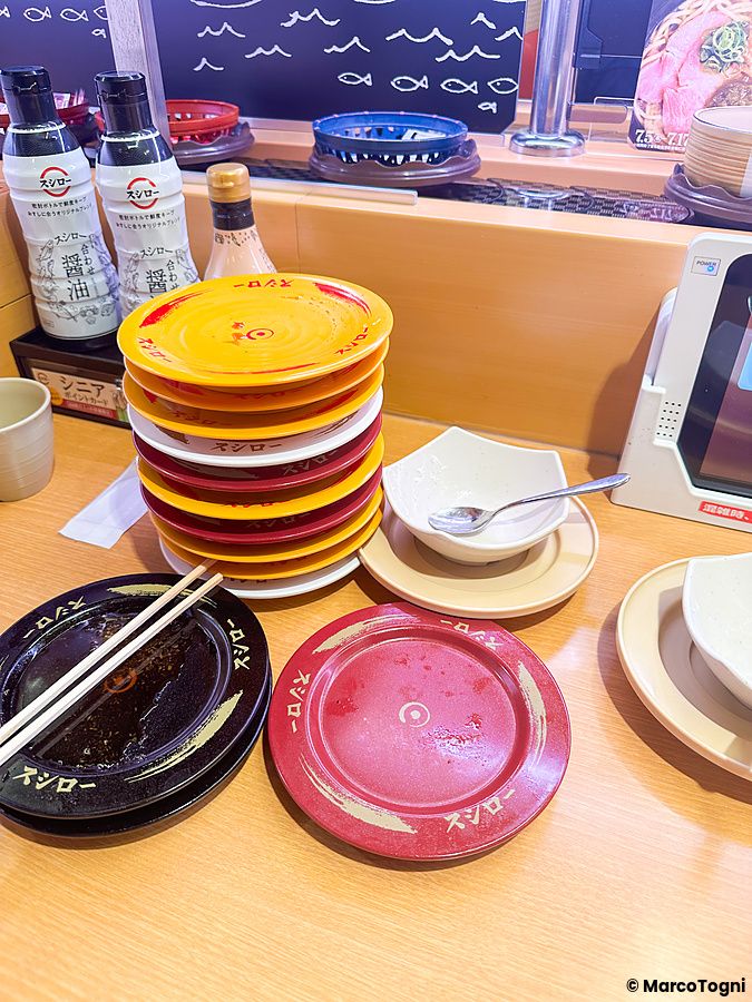Pila di piatti usati con il logo Sushiro su un tavolo in un ristorante in Giappone.