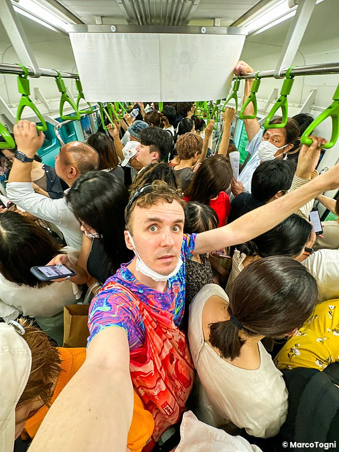 Marco Togni affollato in piedi su un treno in Giappone, con una mascherina.