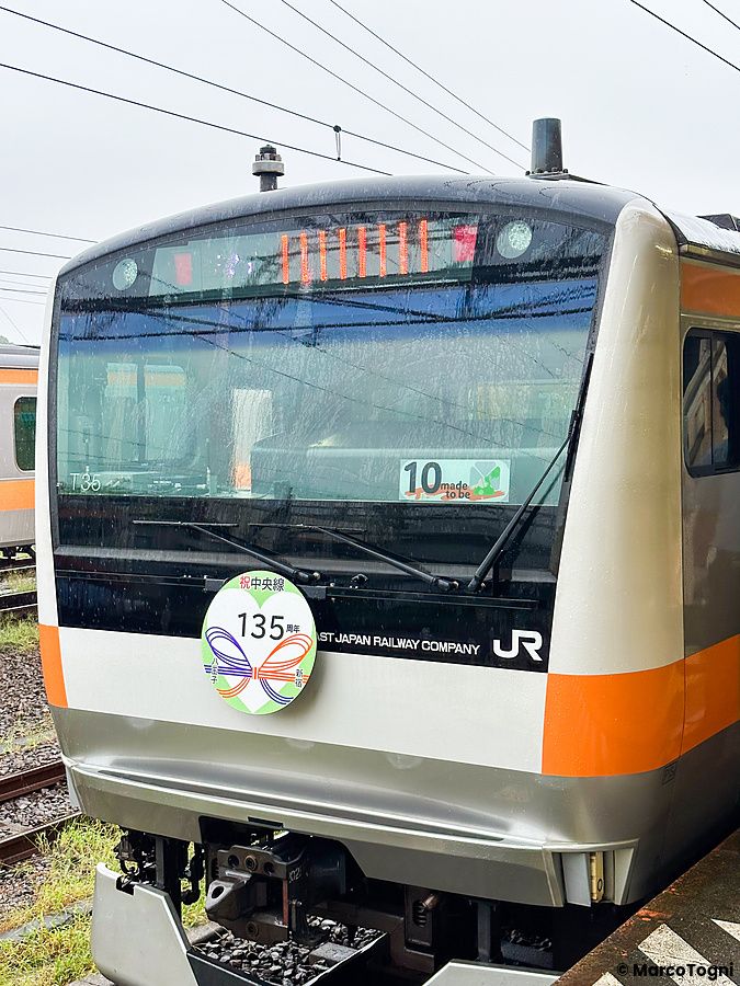 Primo piano del muso di un treno JREast celebrativo per un anniversario in Giappone con un adesivo commemorativo.