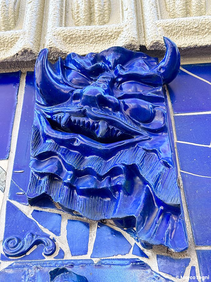 Un bassorilievo in ceramica blu di una maschera demoniaca incastonato in un muro a mosaico a Waseda El Dorado, Tokyo.