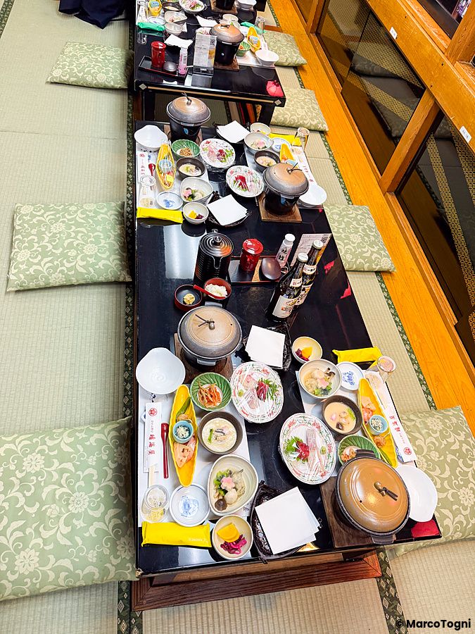 Tavolo da cena imbandito con piatti tipici giapponesi su pavimento in tatami all'interno di una imbarcazione Yakatabune.