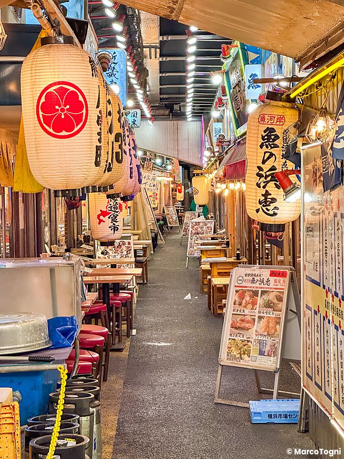 Via stretta con lanterne e tavoli nei ristoranti di Yurakucho Yokocho.