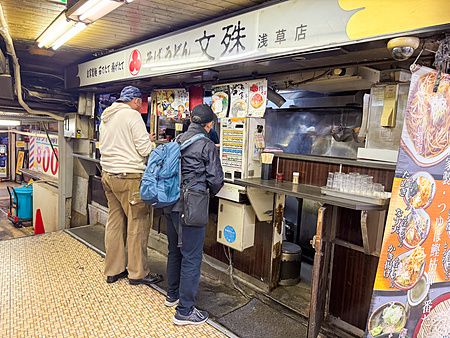 Due persone ordinano il cibo presso un chiosco di noodle nella Asakusa Underground Street.