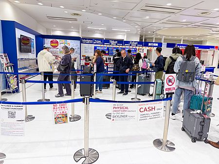 Persone in fila alla biglietteria Skyliner all'aeroporto di Narita.
