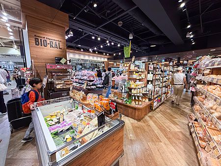 Interno del supermercato Bio-Ral con scaffalature in legno e clienti tra le corsie di prodotti biologici.