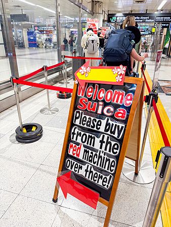 cartello per la carta Welcome Suica all’aeroporto di Narita con persone in coda.