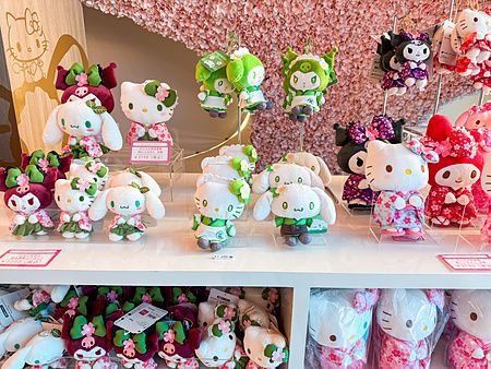 Scaffali bianchi con peluche di Hello Kitty e amici vestiti con abiti tradizionali nel negozio di Hello Kitty Smile.