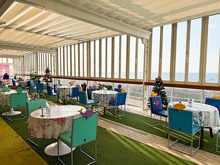 Una sala da pranzo con sedie azzurre e vista mare presso il parco divertimenti Hello Kitty Smile sull'isola di Awaji.