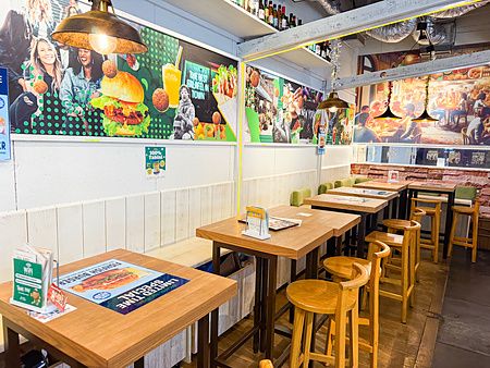 Interno del ristorante Falafel Brothers con tavoli in legno e pareti decorate da poster sui cibi vegani offerti.