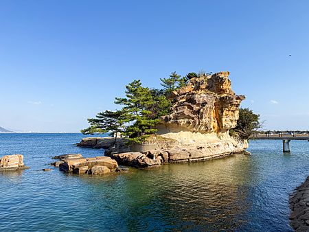 Veduta dell'isola di Eshima (Awaji), una formazione rocciosa di arenaria circondata dal mare con alberi di pino.