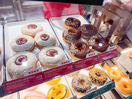 Una selezione di ciambelle Krispy Kreme Doughnuts in Giappone disposte all'interno di una vetrina refrigerata.