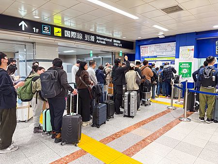 Persone in coda con valigie presso la biglietteria Skyliner all'aeroporto di Narita.