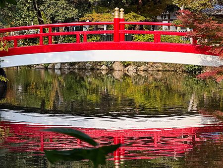 Ponte ad arco rosso e bianco che si riflette nelle acque del Santuario Izanagi nell'isola di Awaji.