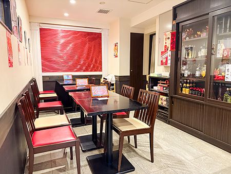 L'interno del ristorante cinese Sairaien a Ueno mostra file di tavoli con sedie bicolore e una parete rossa ondulata.