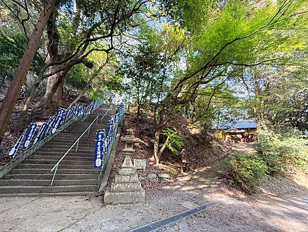 Scalinata in pietra fiancheggiata da stendardi blu presso il Santuario Iwagami sull'isola di Awaji, in Giappone.