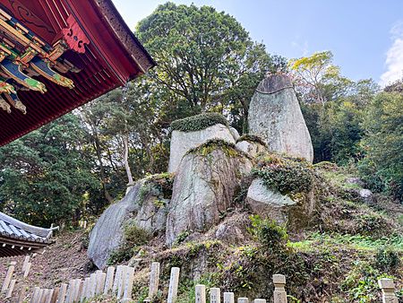 Veduta del masso sacro presso il Santuario Iwagami sull'isola di Awaji, Giappone, circondato da vegetazione.