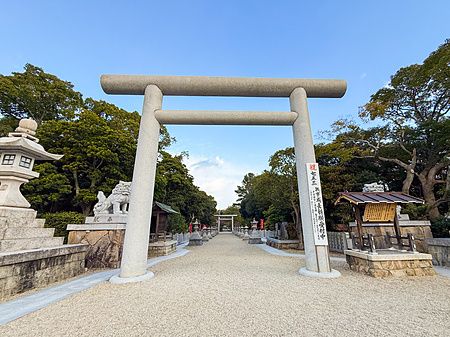 Grande torii in pietra all'ingresso del Santuario Izanagi sull'isola di Awaji, con un sentiero ghiaioso sullo sfondo.