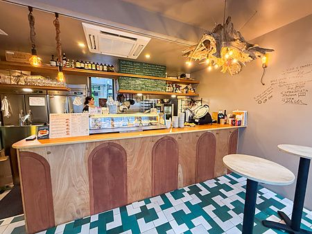 Interno del ristorante Tutu a Meguro con bancone in legno, pavimento geometrico e scritte alle pareti.