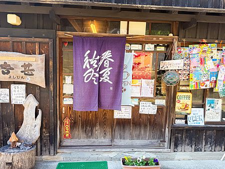 Ingresso in legno dello Yoshijin Battari Cafe sull'isola di Nushima in Giappone con noren viola appesa alla porta.