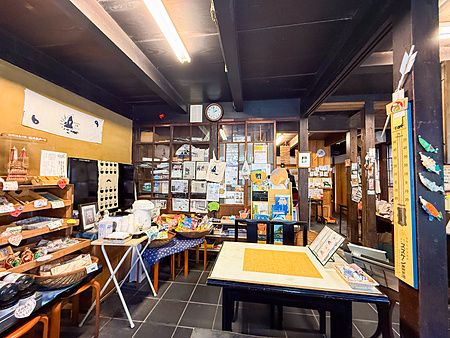 Vista interna dello storico Yoshijin Battari Cafe sull'isola di Nushima con tavoli, scaffali e oggettistica varia.