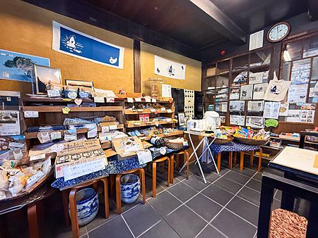Interno del negozio Yoshijin Battari Cafe sull'isola di Nushima con scaffali in legno pieni di prodotti locali.