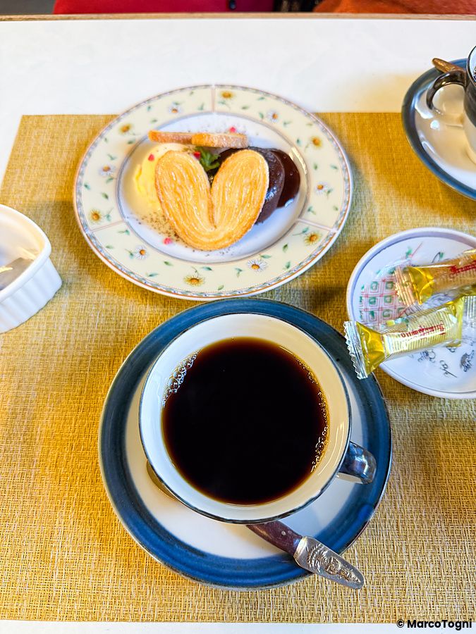 Una tazza di caffè e un piatto con un dolce a forma di cuore serviti presso il Yoshijin Battari Cafe a Nushima.