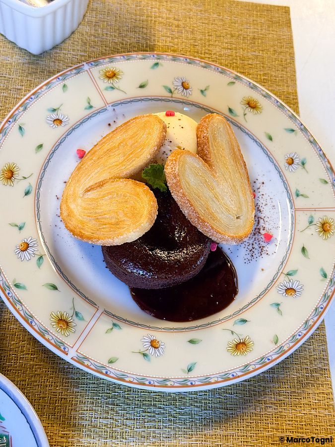 Un tortino al cioccolato con sfoglie a forma di cuore e gelato servito su un piatto floreale al Yoshijin Battari Cafe.