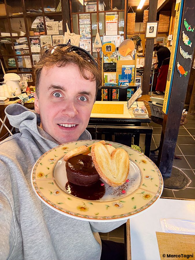 Marco Togni tiene in mano un piatto con caffè e dolce all'interno dello Yoshijin Battari Cafe sull'isola di Nushima.
