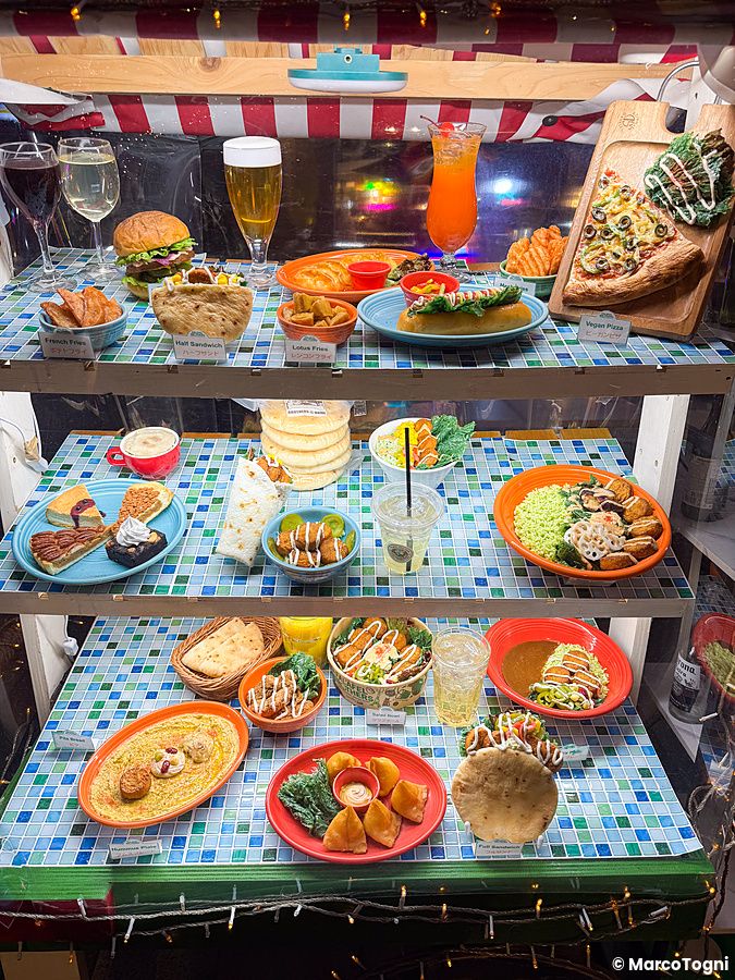 Una vetrina di un ristorante Falafel Brothers in Giappone che espone modelli in plastica di cibi vegani su vari piani.