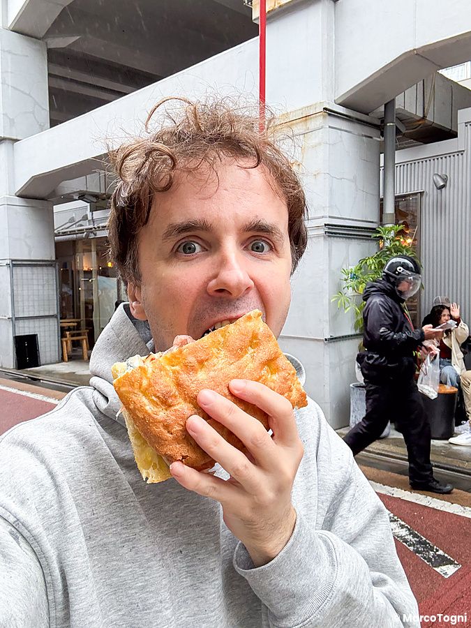 Marco Togni mangia una focaccia con prosciutto davanti al ristorante Tutu nella zona di Meguro a Tokyo.