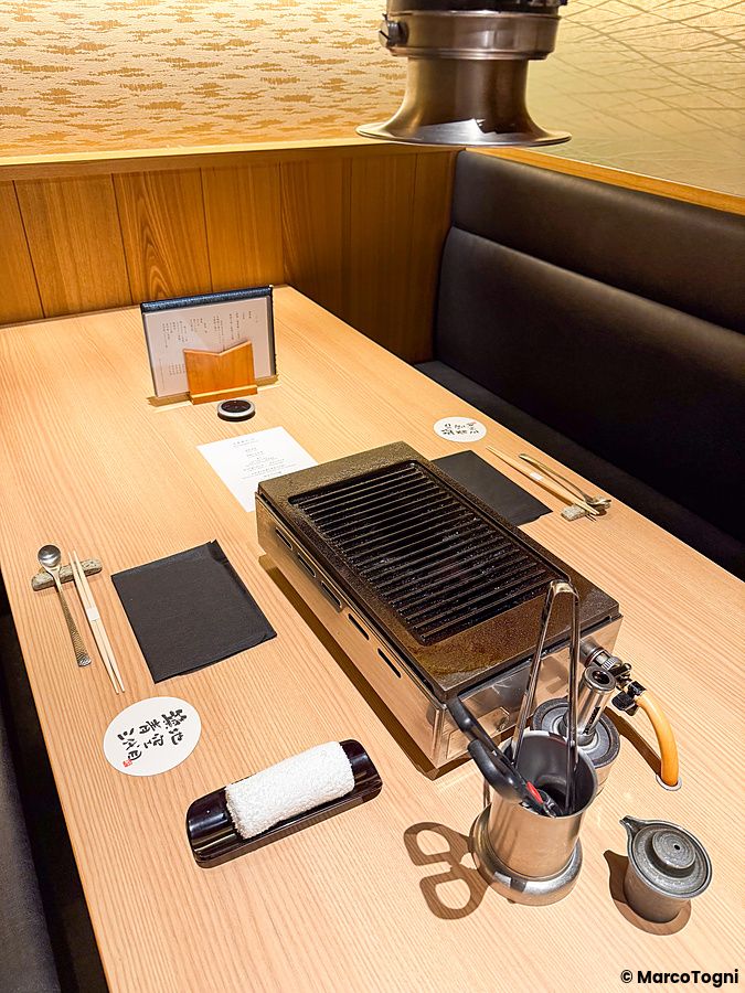 Tavolo apparecchiato con griglia centrale per cucinare pesce al tavolo a Yakiuo Ishikawa a Roppongi.