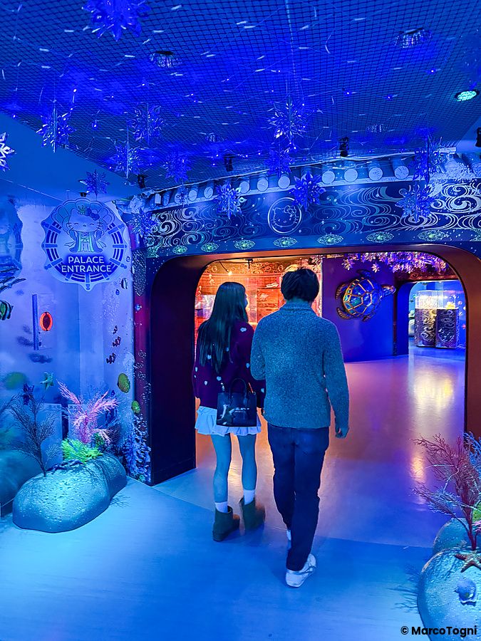 Una coppia cammina in un corridoio illuminato di blu all'interno di Hello Kitty Smile sull'isola di Awaji.