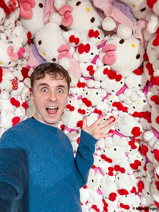 Marco Togni si scatta un selfie davanti a una parete ricoperta di decine di peluche di Hello Kitty a Hello Kitty Smile.