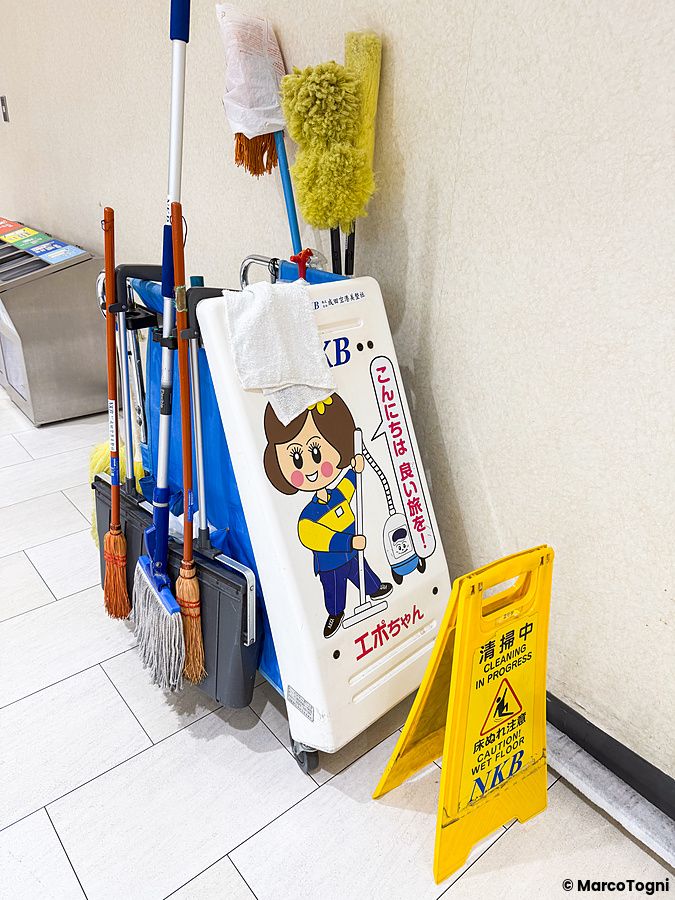 Carrello per pulizie con attrezzi e cartello in giapponese all'aeroporto di Narita.