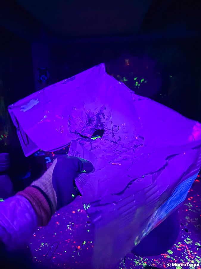 Una mano con guanto protettivo tiene un oggetto di cartone danneggiato nella rage room a Reeast Room a Ikebukuro.