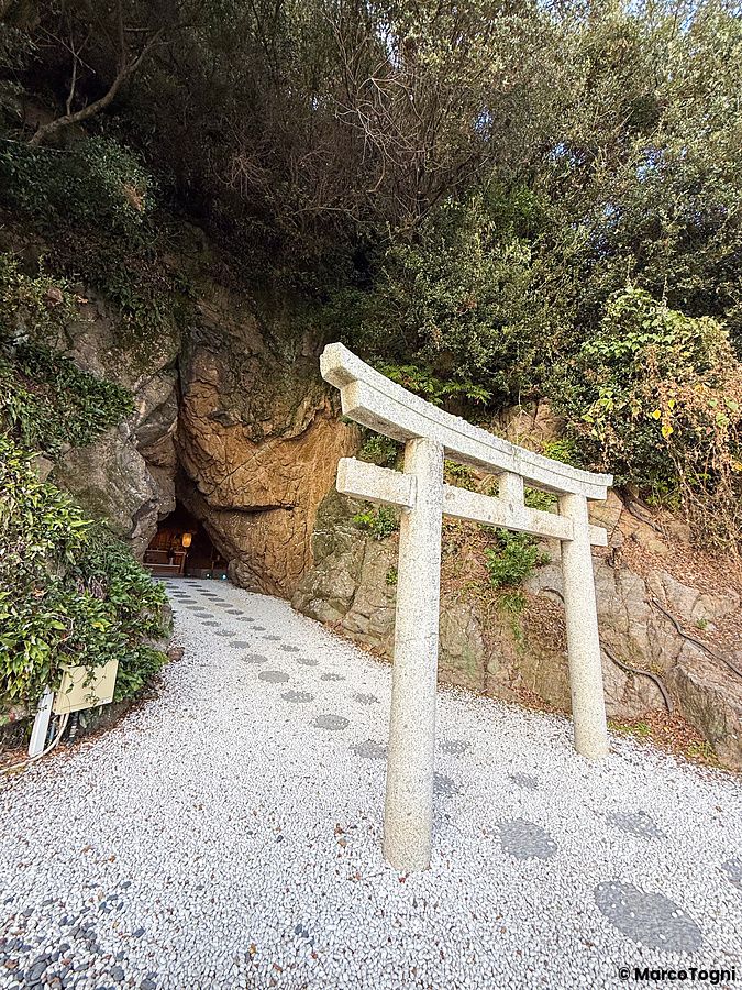 Il Santuario Aiga Iwato Shinryu nell'isola di Awaji, Giappone, con un torii di pietra all'ingresso di una grotta marina.