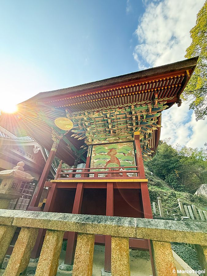 Veduta dal basso della struttura principale del Santuario Iwagami sull'isola di Awaji con il suo masso sacro alle spalle.