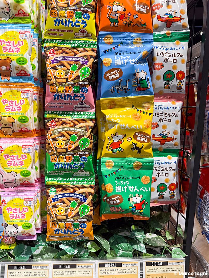 Scaffali di snack confezionati e prodotti biologici esposti ordinatamente all'interno di un supermercato Bio-ral.