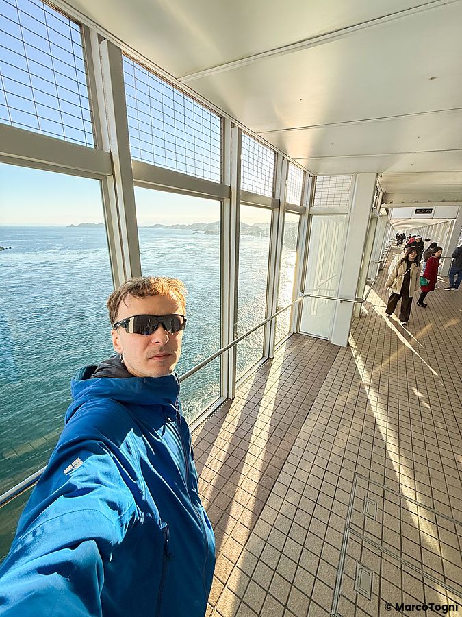 Marco Togni in giacca blu scatta un selfie all'interno del ponte dove si vedono i vortici a Vortice di Naruto in Giappone.