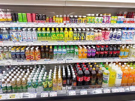 Scaffali colmi di bibite in un convenience store in Giappone, con una grande varietà di lattine e bottiglie colorate.