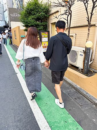 coppia a Shibuya cammina mano nella mano lungo un marciapiede